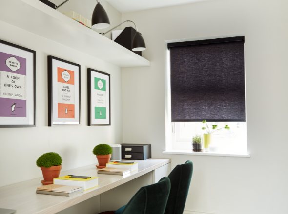 A black roller blind in a minimalist office room with coloured artwork on the walls