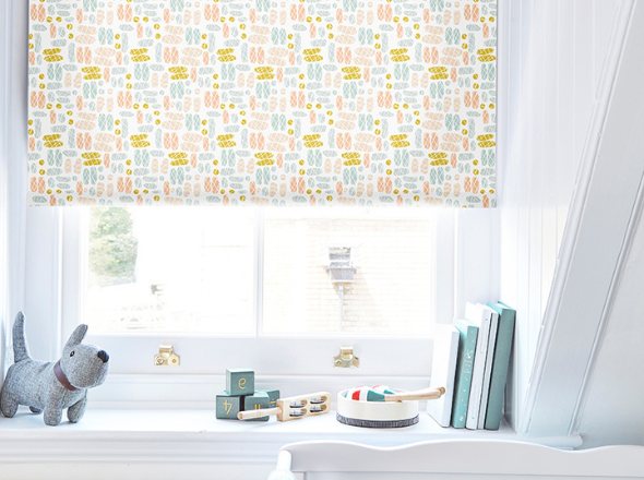 A patterned children's roller blind in a window with a dog toy and books