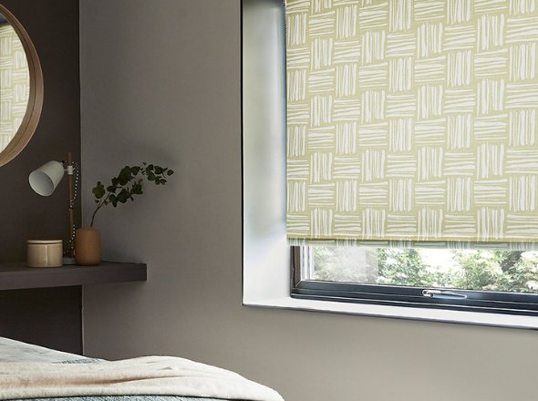 A green patterned roller blind in a modern bedroom with grey slate walls