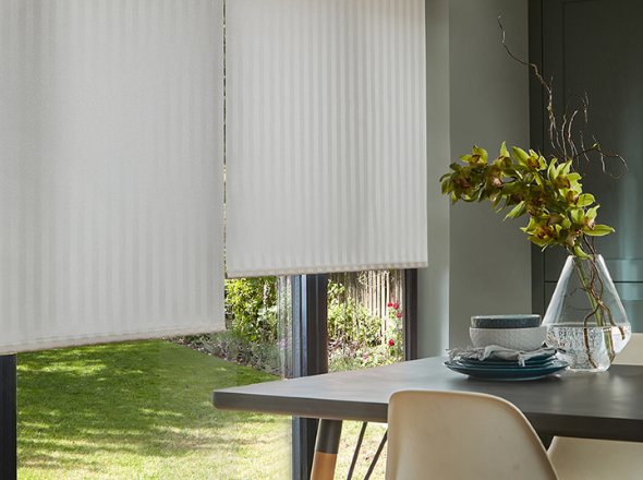 A white roller blind in a minimalist bedroom with neutral tones