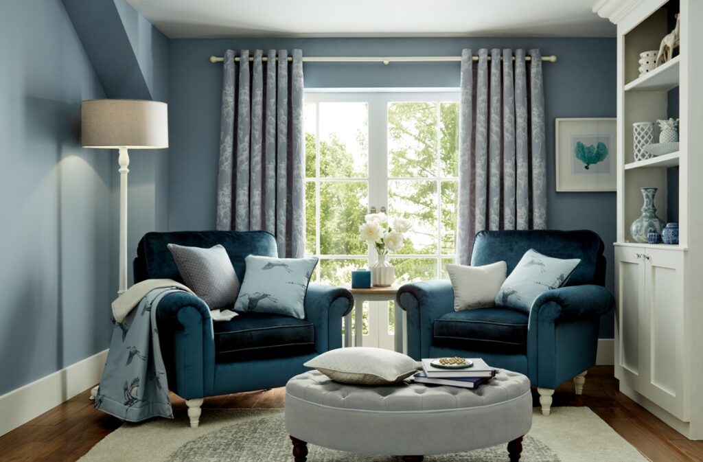 Blue eyelet curtains set on a white curtain pole which matches the white furniture and skirting boards