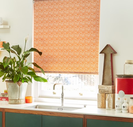 A orange coloured blind in a modern kitchen with plants
