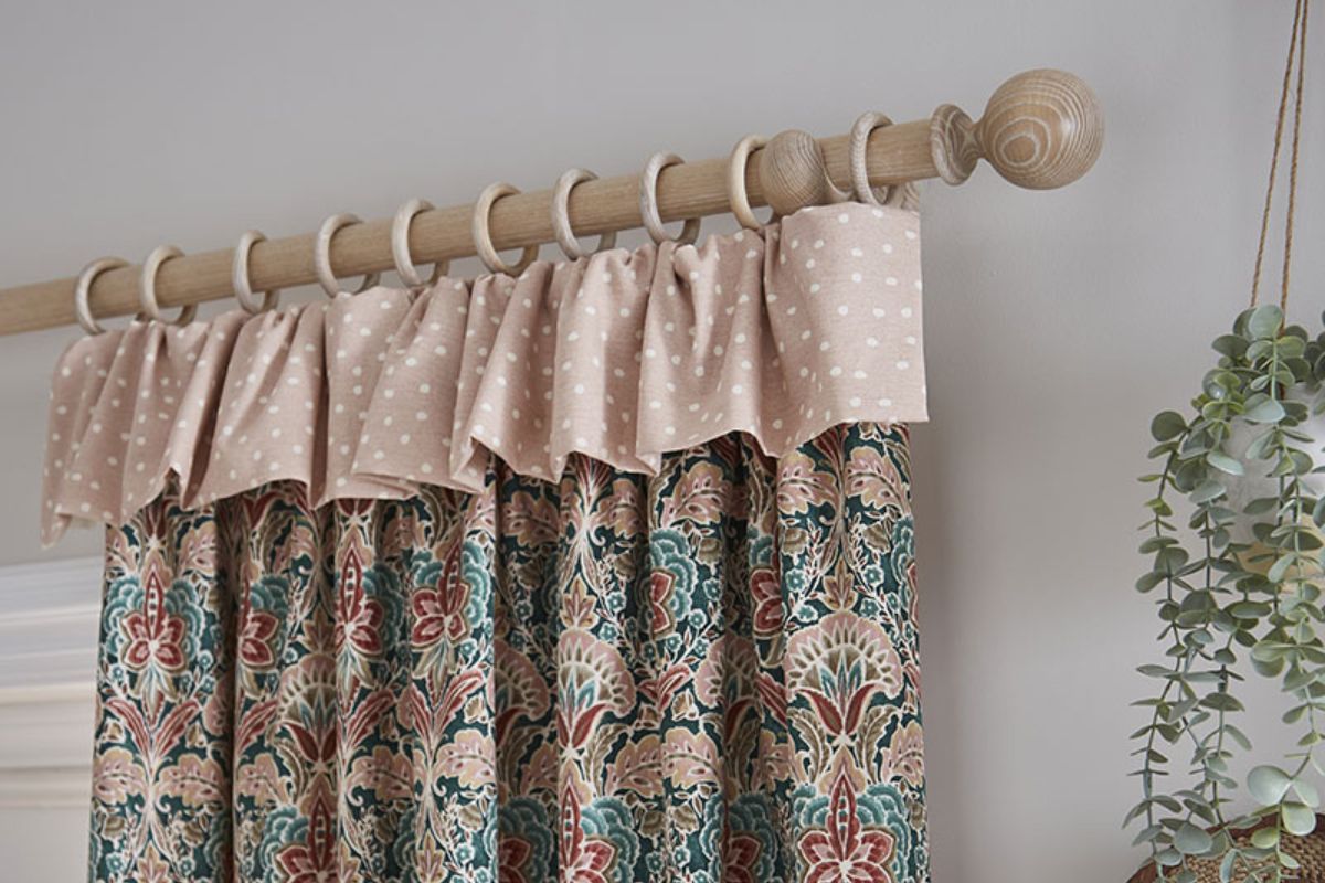 A sand coloured Hallis Hudson Eden wooden curtain pole with patterned curtains