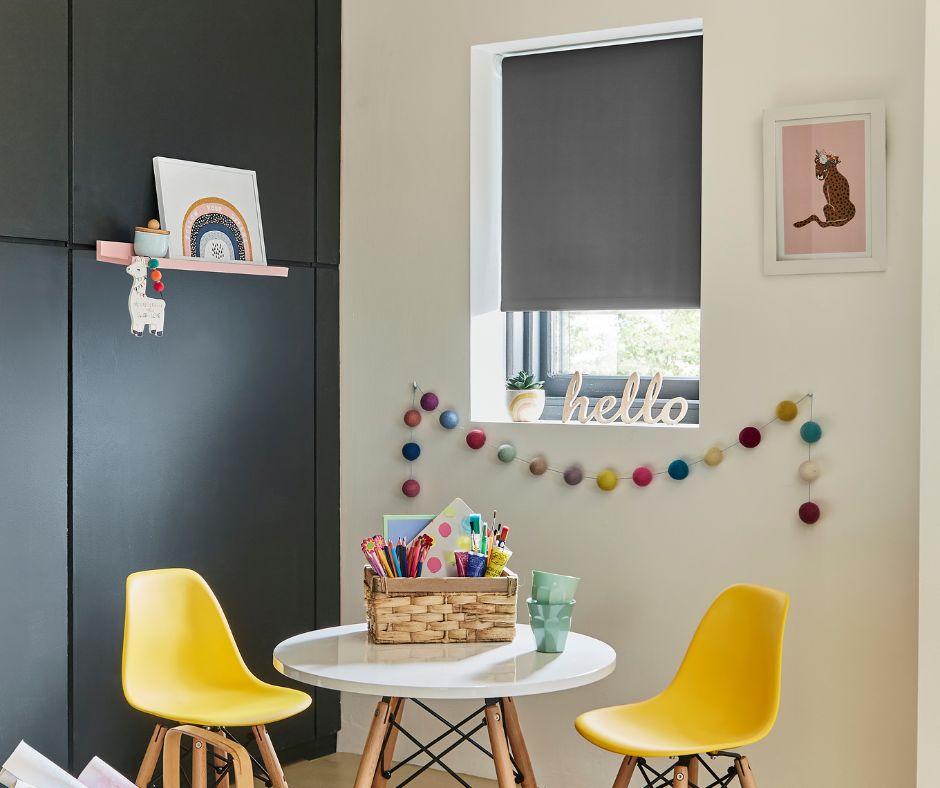 A grey roller blind in a childrens play room with yellow seats