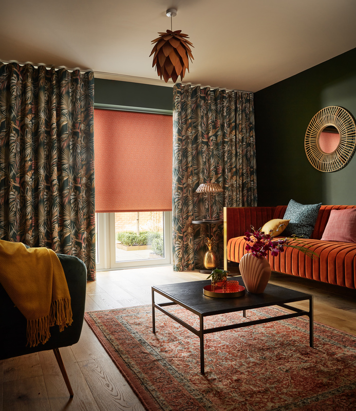 Orange roller blind layered with patterned curtains in a cosy living room