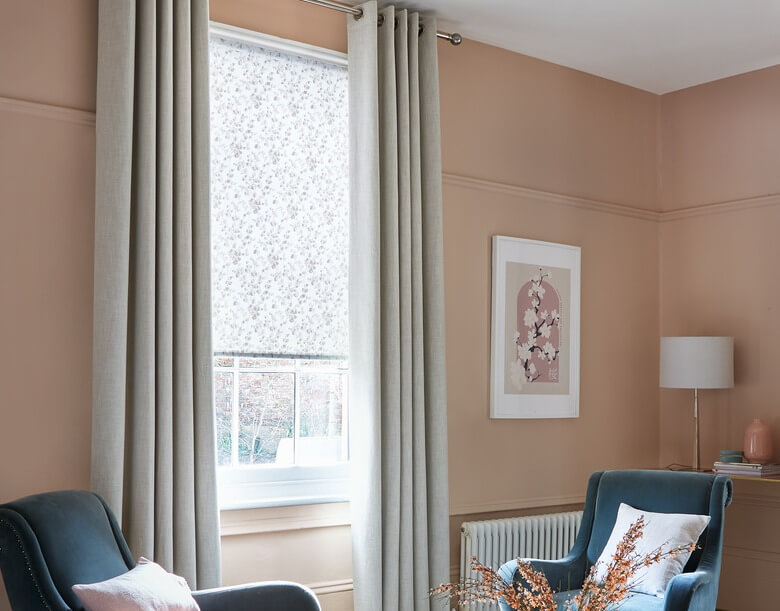 A patterned curtain framing a living room window with insulating blind