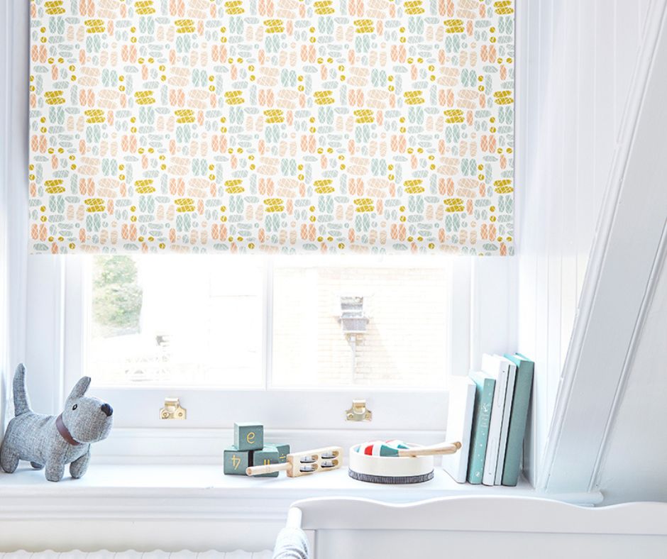 A yellow patterned children's blind hung above a childs cot