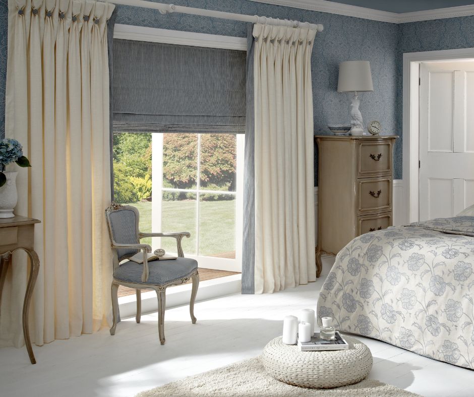A grey roller blind and cream cutrain hung in a modern bedroom