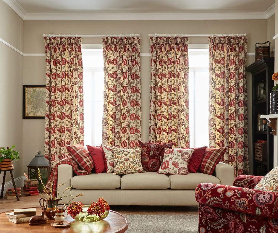A pair of red curtains hanging in a cosy living room with cream sofa